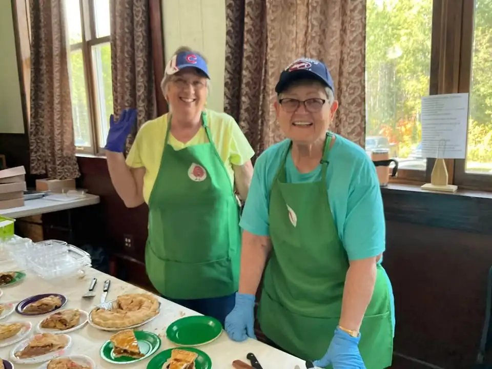 Volunteers in green aprons serving homemade apple pies at the Beechwood Apple Festival